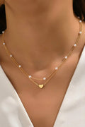 Gold necklace with heart pendant on a model wearing a white top