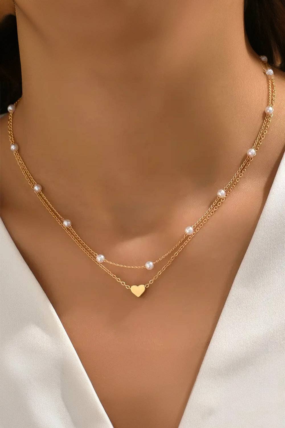 Gold necklace with heart pendant on a model wearing a white top