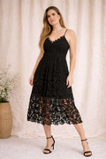 Woman wearing a black lace dress against a beige curtain background