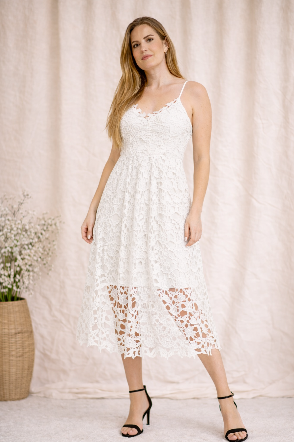 Woman wearing a white lace dress against a neutral background
