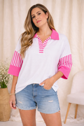 Woman wearing a white shirt with pink accents and denim shorts in a casual setting.