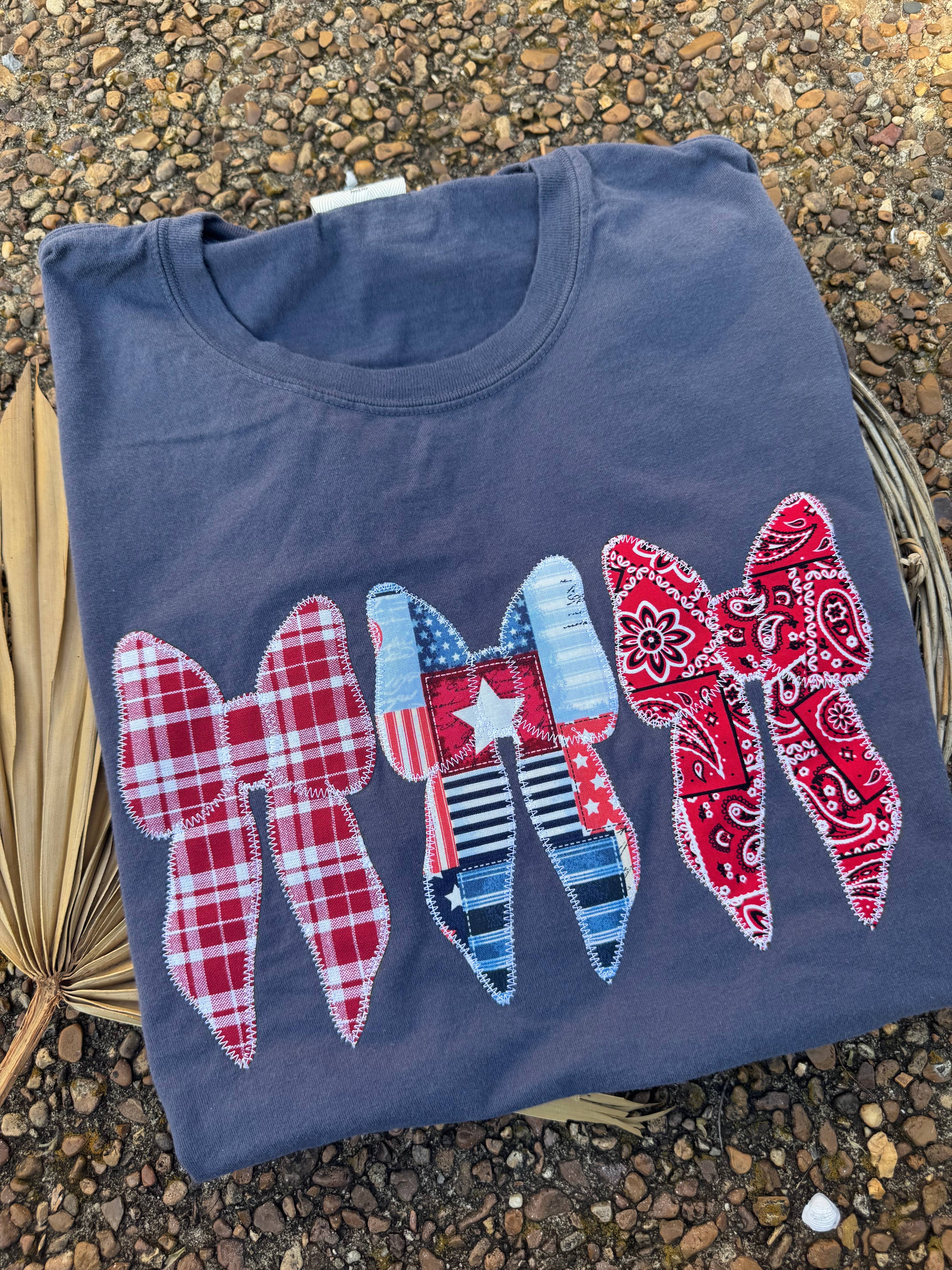 Folded blue t-shirt with decorative bows on a textured surface
