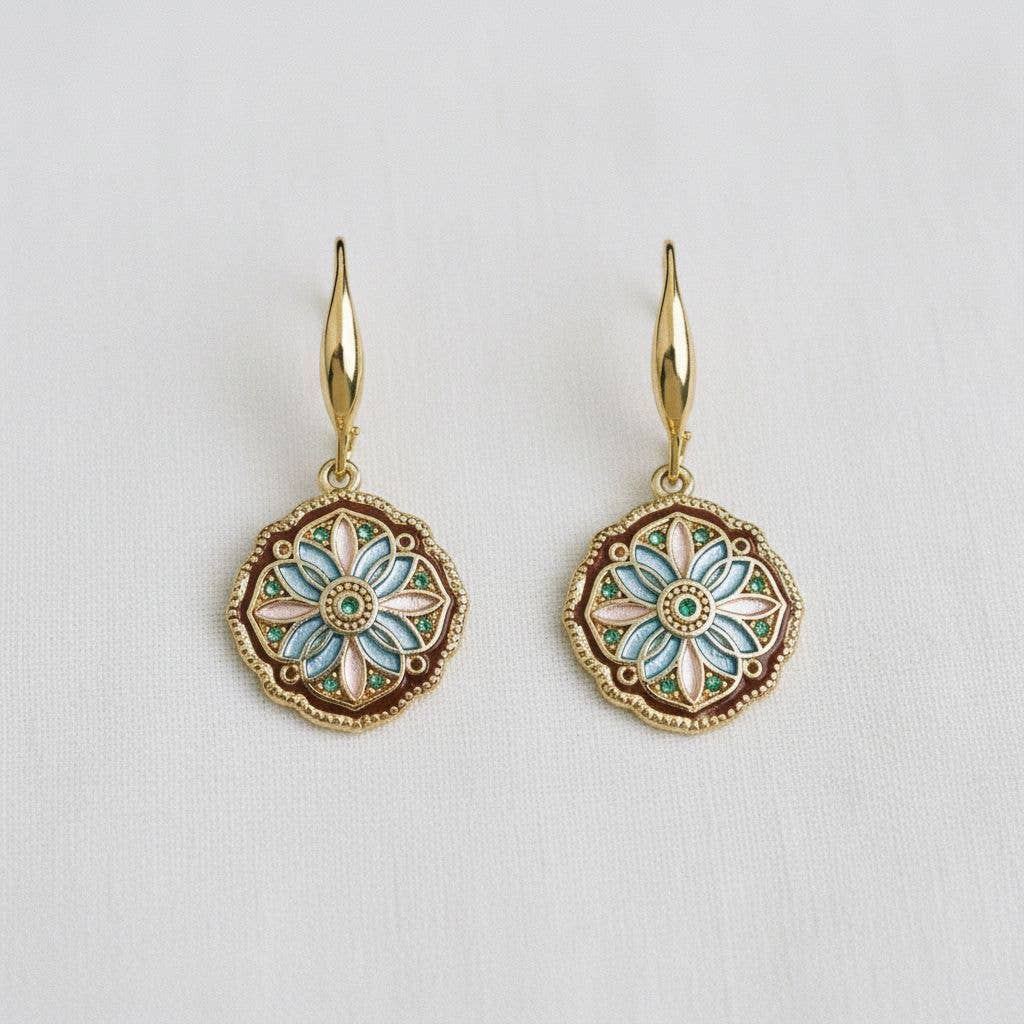 Gold earrings with floral designs on a light gray background