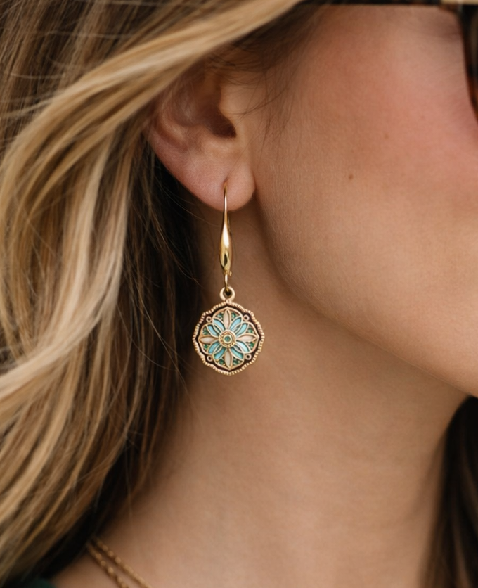 Close-up of a woman wearing a gold earring with a blue gemstone.