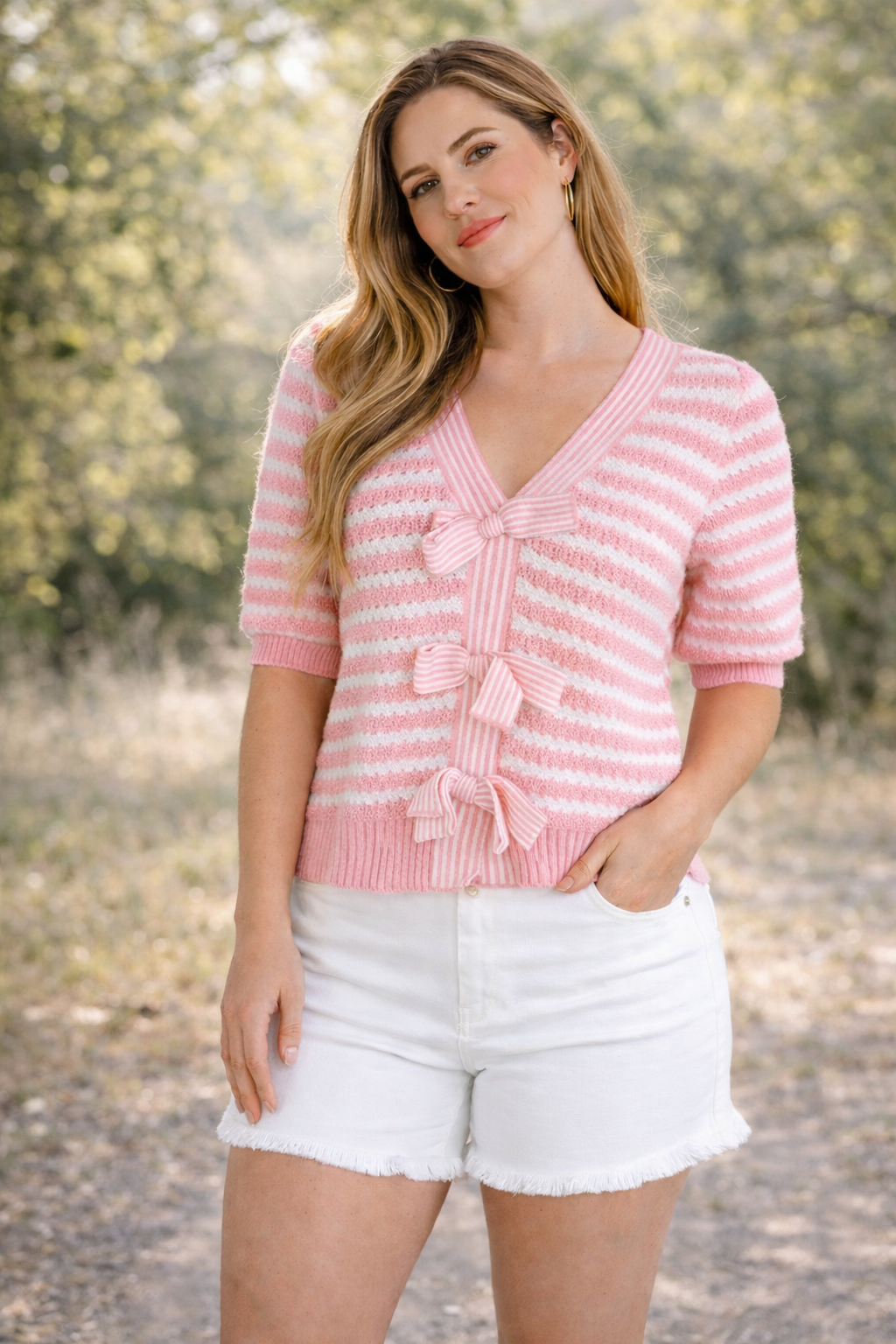 Woman wearing a pink striped sweater and white shorts outdoors
