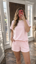 Person wearing a pink striped pajama set taking a mirror selfie.